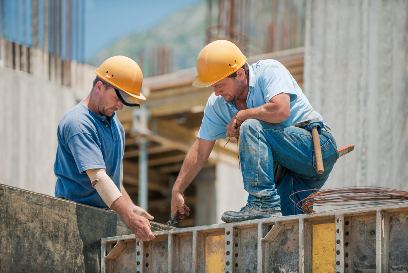 Two construction workers in hard hats engaged in building work.