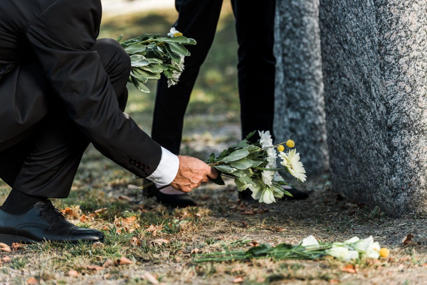 A person in a suit places flowers on a grave, a poignant moment reflecting wrongful death litigation.