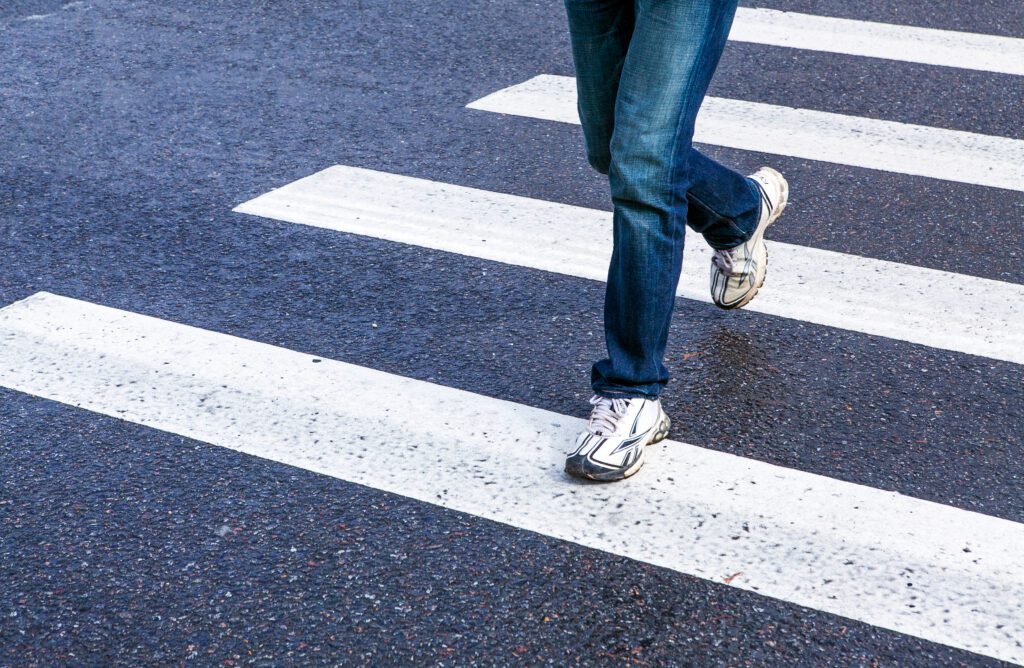 Person walking across a zebra crossing, a common setting for pedestrian accidents to occur.