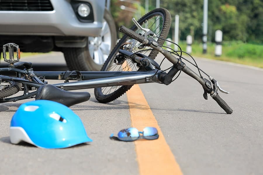 Bicycle lies down on a road after a collision with car.