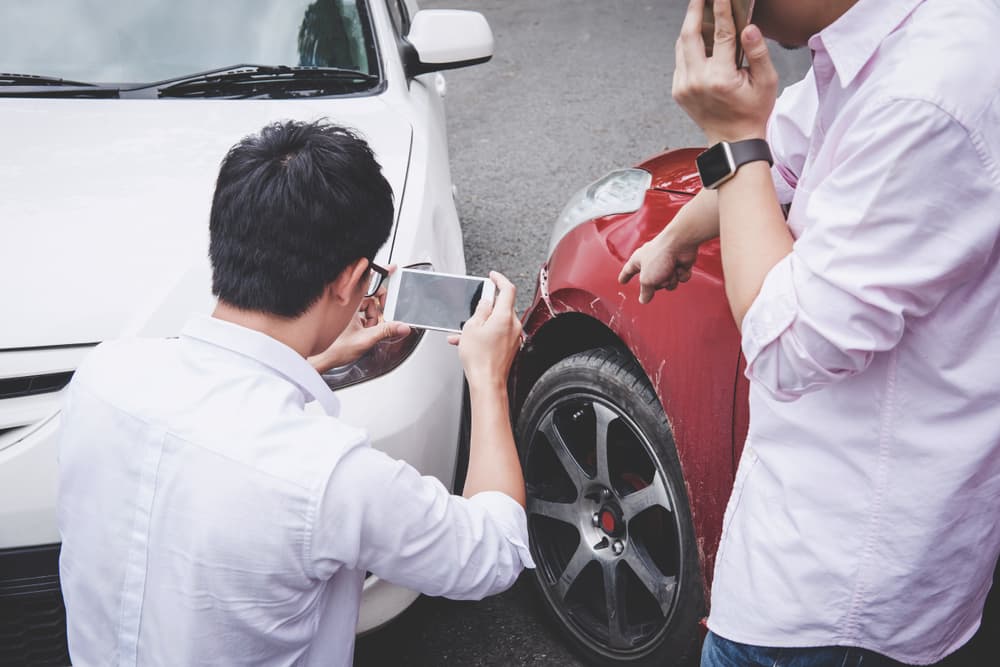 Two drivers argue post-accident, call police to report the accident, and take photos.