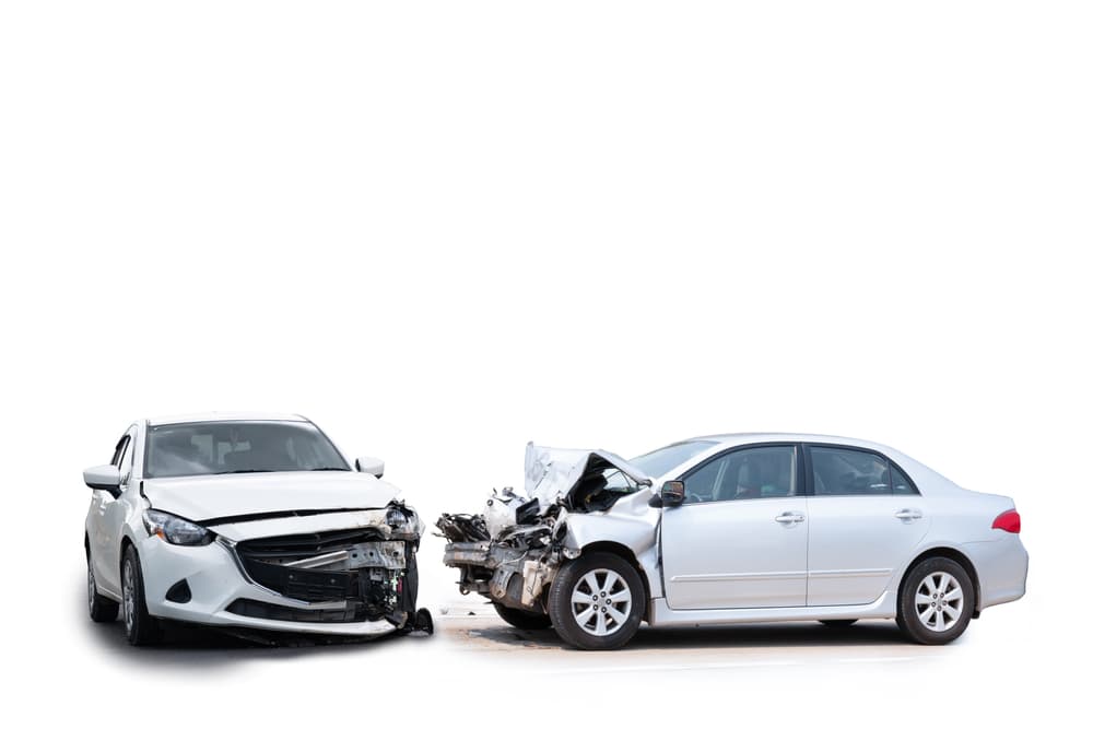 A white car has sustained damage to its front as a result of a road accident. The image is isolated on a white background.
