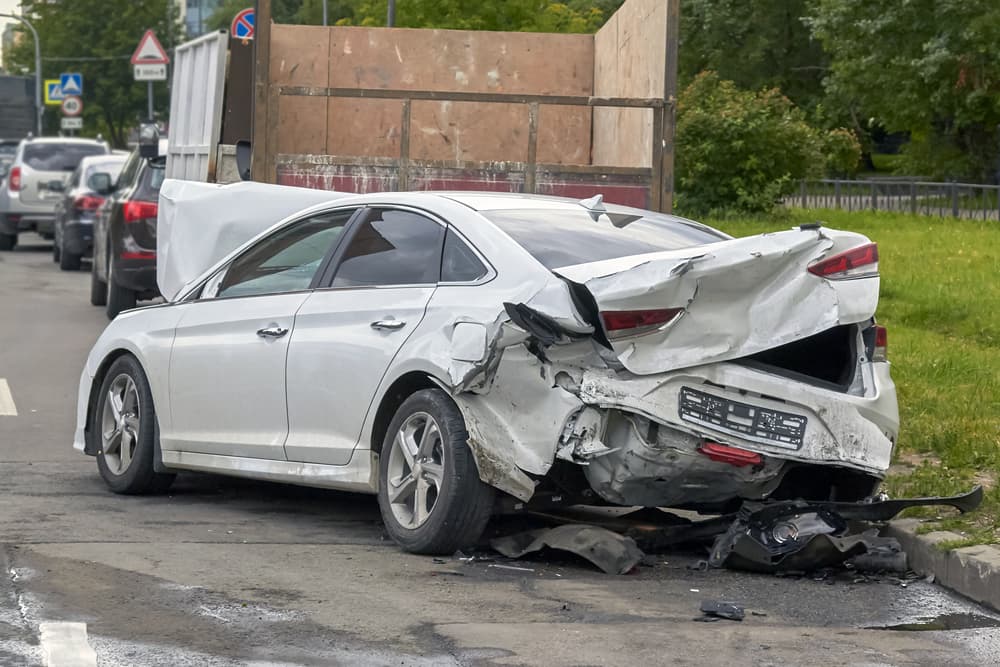 The car's front hood, headlights, rear trunk, and bumper are irreparably damaged, resulting in a total loss.