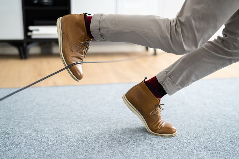 A negligent slip and fall incident occurs as feet stumble over a wire cord, highlighting the hazards of neglecting safety measures.