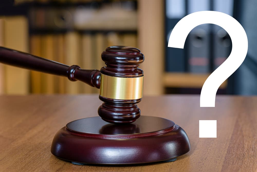 Close-up Of Question Mark Sign With Gavel Over Wooden Desk
