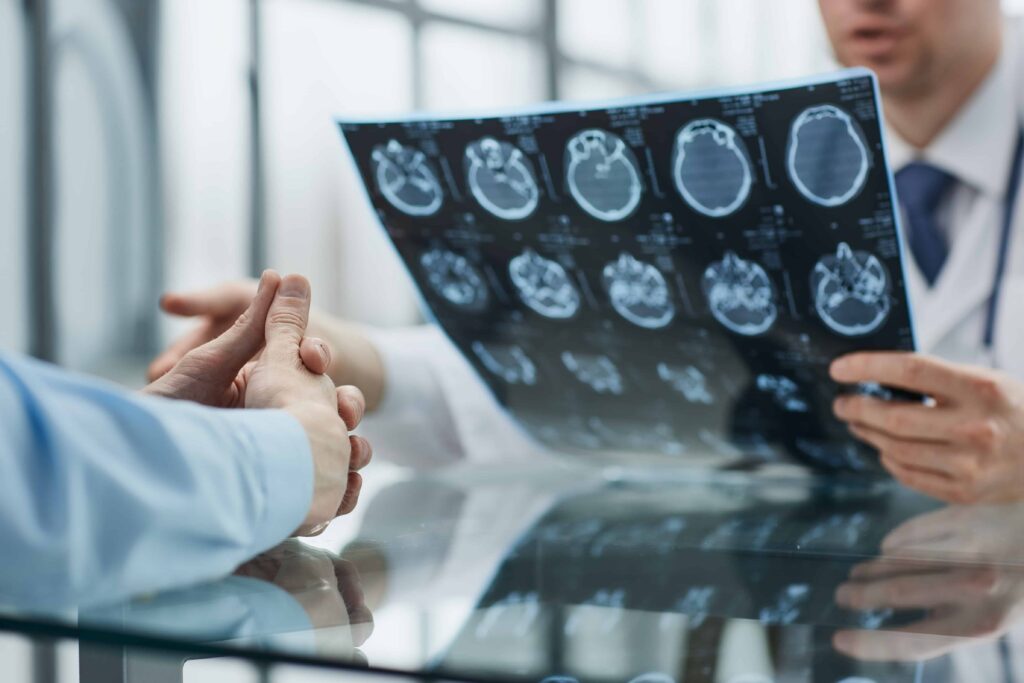 Doctor reviewing patient&rsquo;s brain scan results and discussing diagnosis in medical office.