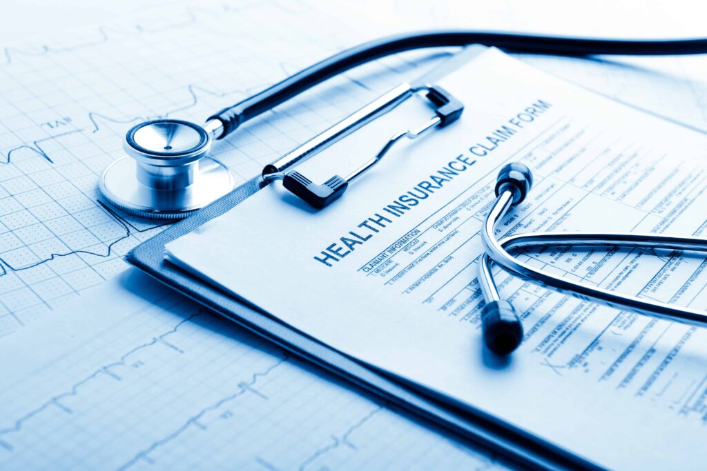 Health insurance claim form with stethoscope on medical chart background.