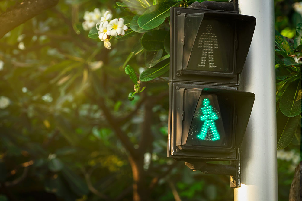 Pedestrian crossing signal displaying a green walking figure and a red standing figure above it at an intersection