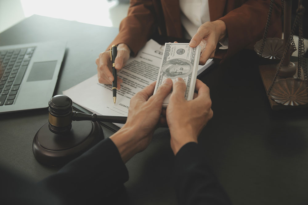 Lawyer’s desk with money and a check, illustrating how contingency fees and case expenses are deducted from a personal injury settlement