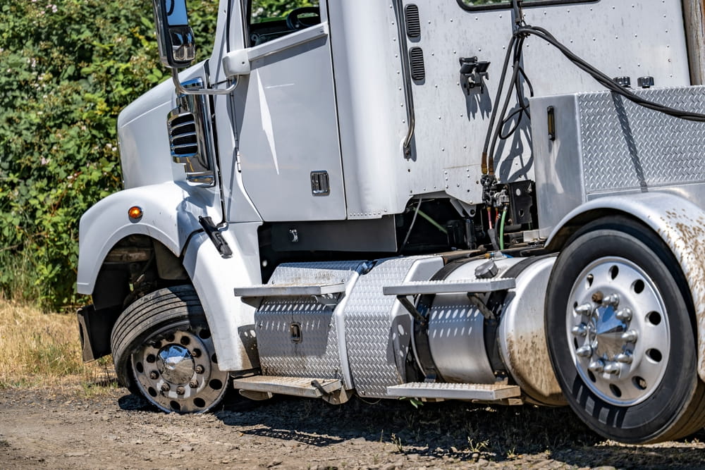 Commercial truck with damaged wheel and mechanical components involved in a collision